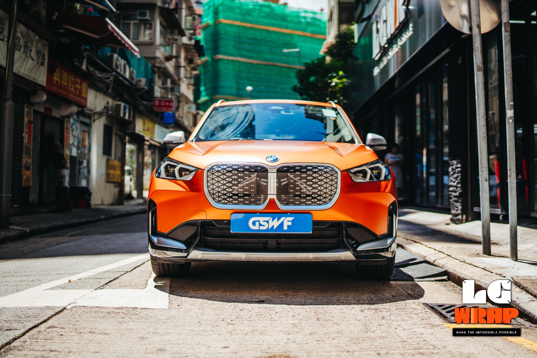 Street shot of an orange matte BMW iX1 front, showcasing Matte Colour PPF effect and kidney grille