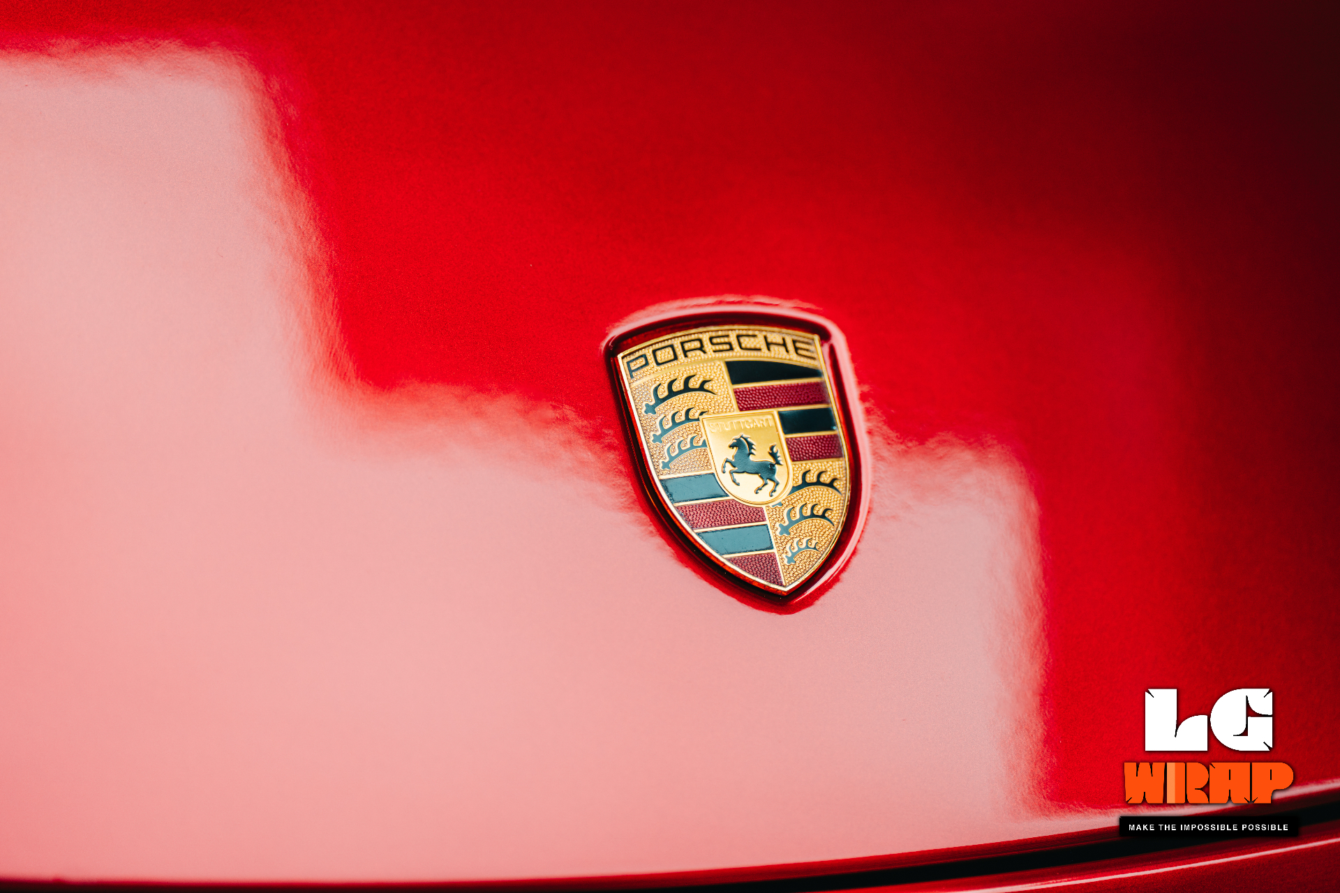 Close-up of a red Porsche hood crest, showing the PTS paint gloss and premium texture