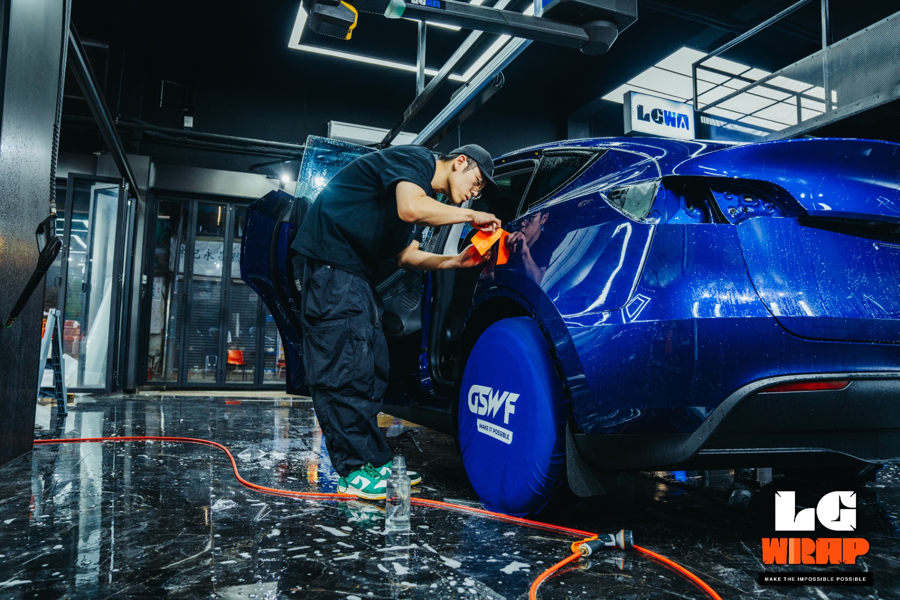 LGWR technician stretching and applying GSWF PPF to the side of a blue Tesla Model Y