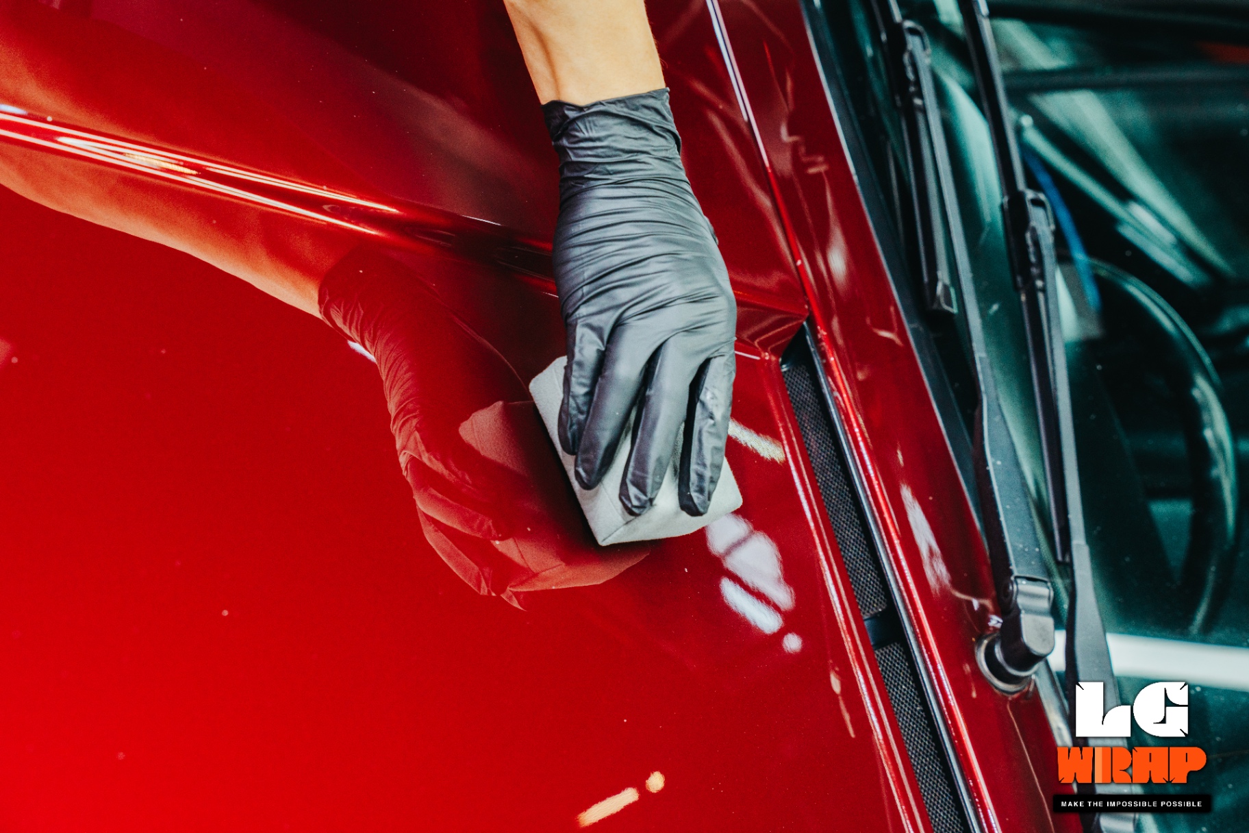 Technician using clay bar for deep decontamination on Porsche 993 burgundy paint