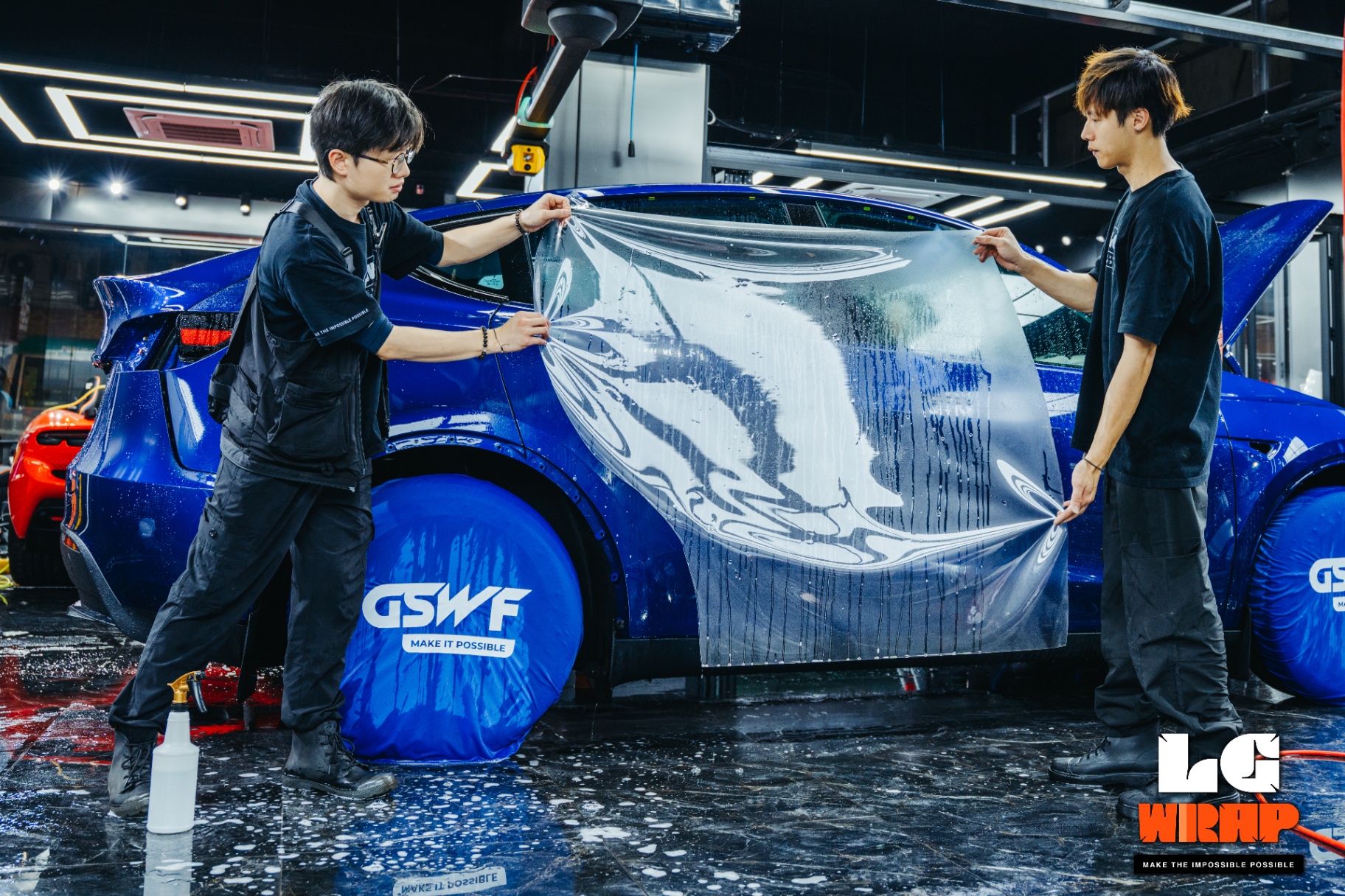 Two LGWR technicians working together to install GSWF TPU clear PPF on a Tesla Model Y