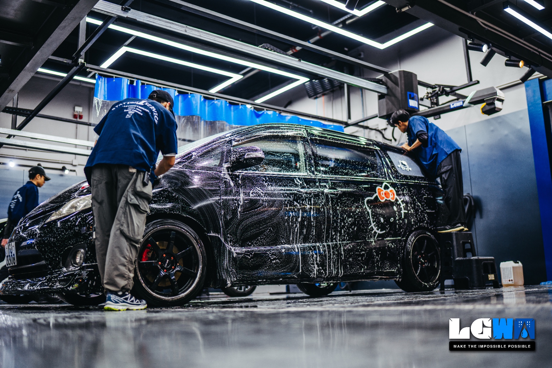 LGWR technician team performing KOCH-CHEMIE certified professional car wash and PPF care for a dark car body in-store