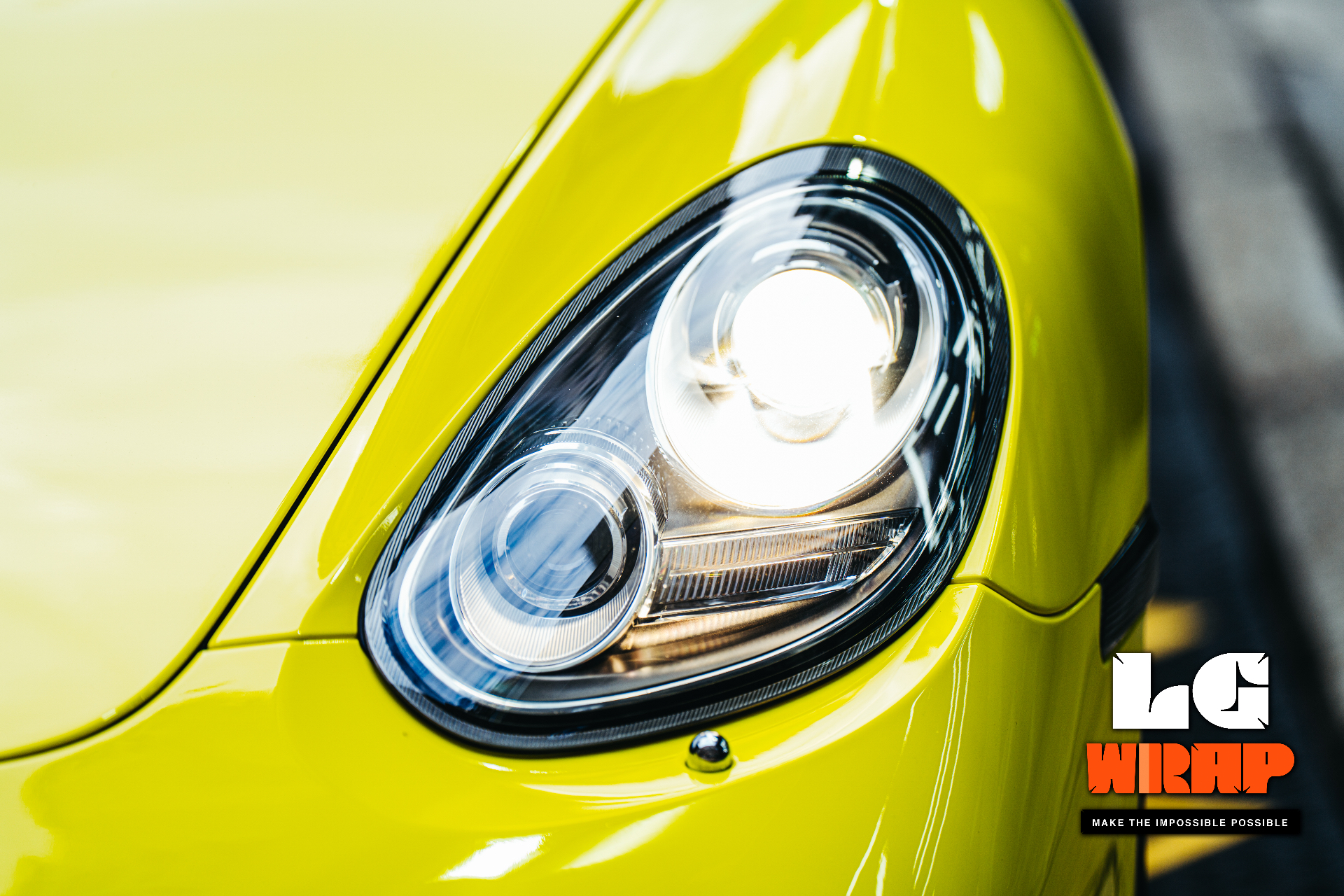 Close-up of a yellow Porsche's headlight and fender, showing fine lines and high-gloss paintwork