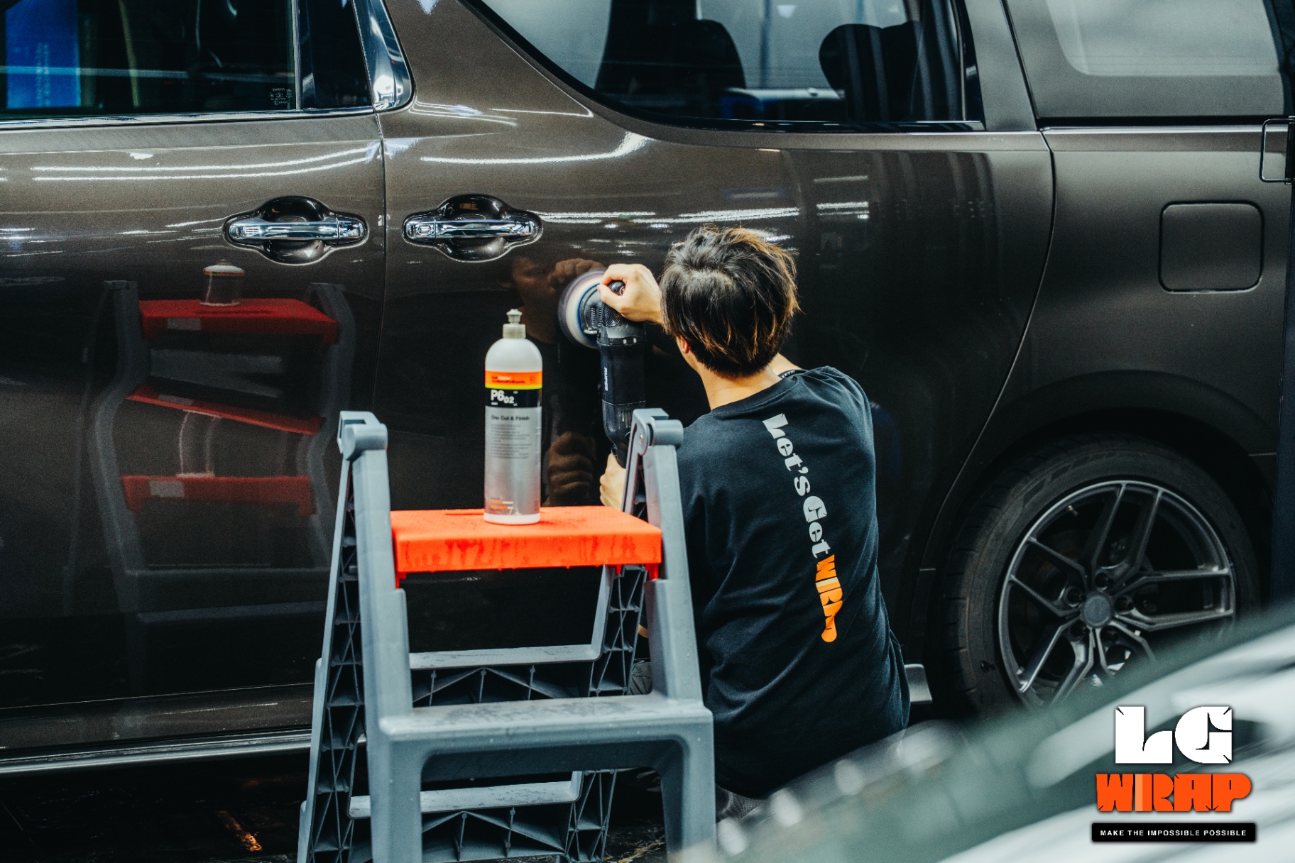 Technician applying P6.02 to the side of a dark brown MPV for polishing